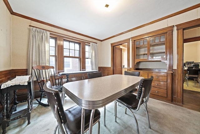 dining area featuring ornamental molding and a wainscoted wall