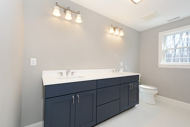 bathroom featuring toilet, dual bowl vanity, and tile patterned flooring