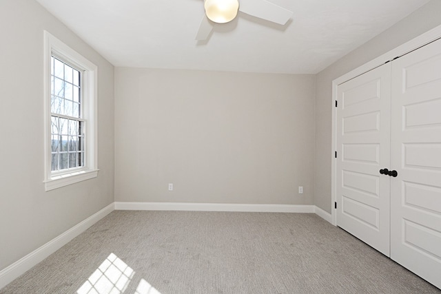 unfurnished bedroom with ceiling fan, a closet, light colored carpet, and multiple windows