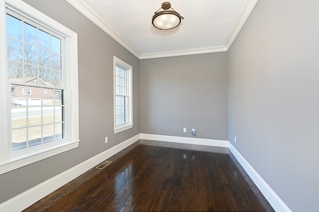 empty room featuring ornamental molding, hardwood / wood-style flooring, and a healthy amount of sunlight