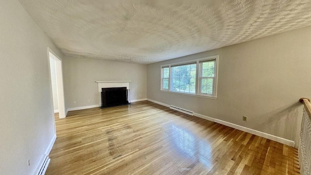 9 Brooks Rd, Sudbury, MA 01776 - unfurnished living room featuring baseboards, a baseboard radiator, a textured ceiling, and wood finished floors