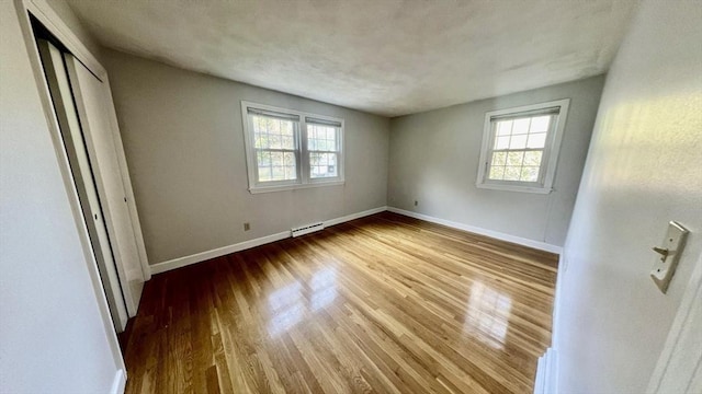 9 Brooks Rd, Sudbury, MA 01776 - unfurnished bedroom with baseboards, multiple windows, a closet, and wood finished floors