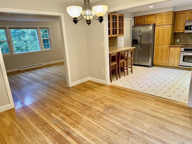 9 Brooks Rd, Sudbury, MA 01776 - kitchen with a baseboard radiator, baseboards, a chandelier, light wood-style floors, and appliances with stainless steel finishes