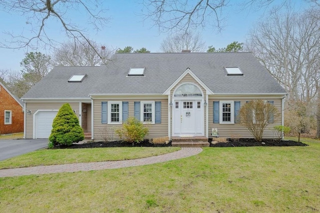 new england style home featuring an attached garage, a front lawn, roof with shingles, and asphalt driveway