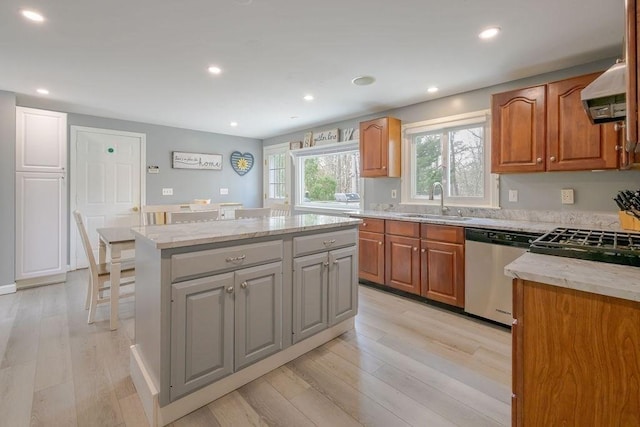 kitchen with stainless steel dishwasher, a sink, a kitchen island, light wood-style flooring, and recessed lighting