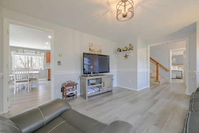 living area featuring light wood-style flooring, stairs, and baseboards