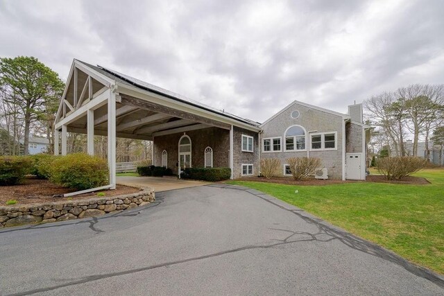 view of front of property with asphalt driveway, a chimney, a front yard, and an attached carport