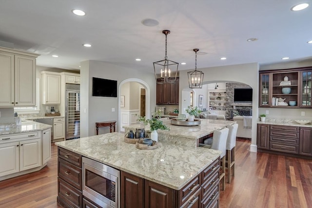 kitchen with dark hardwood / wood-style floors, dark brown cabinetry, built in appliances, and hanging light fixtures