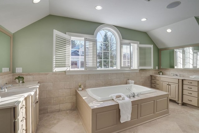 bathroom with lofted ceiling, tile walls, vanity, tiled bath, and tile patterned floors