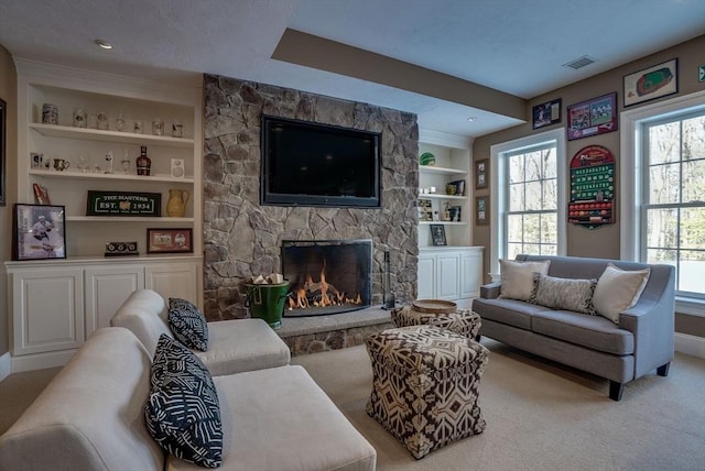 living room featuring a stone fireplace, carpet floors, and built in features