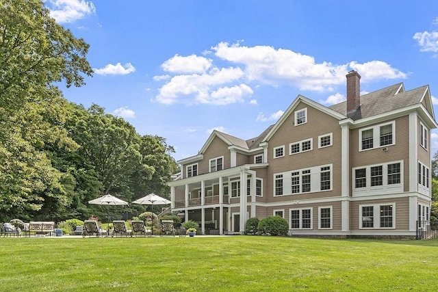 rear view of house featuring a lawn and a sunroom