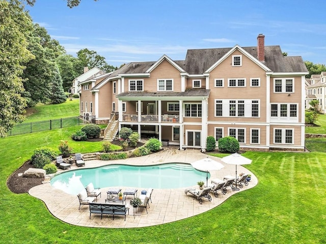 back of property with a fenced in pool, a yard, and a patio area