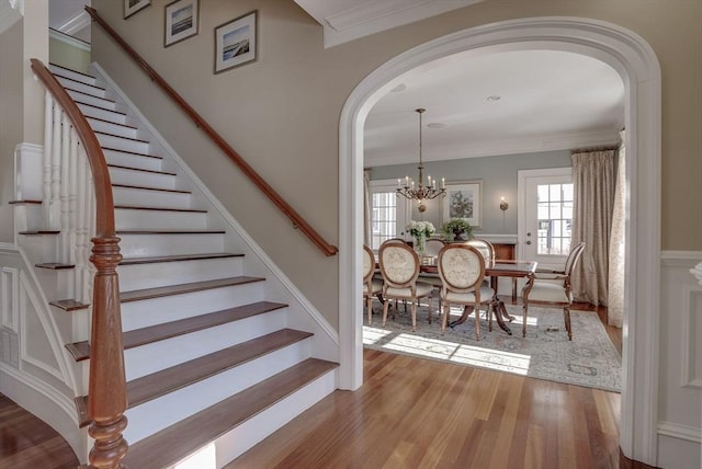 stairway featuring hardwood / wood-style flooring, ornamental molding, and a notable chandelier