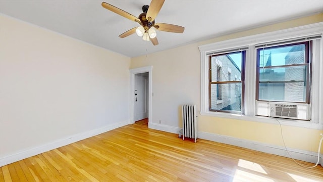 empty room featuring light hardwood / wood-style floors, ceiling fan, cooling unit, and radiator