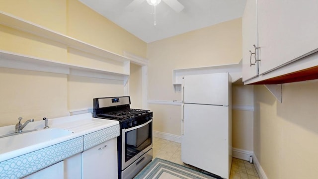 kitchen featuring sink, white cabinets, white fridge, stainless steel gas range, and ceiling fan