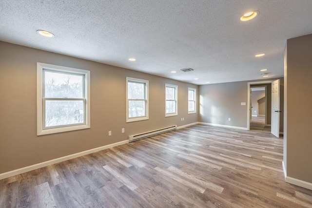 unfurnished room featuring a baseboard heating unit, a textured ceiling, and light wood-type flooring