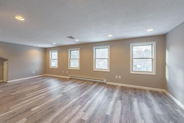 unfurnished room with a baseboard radiator, a textured ceiling, and light hardwood / wood-style flooring