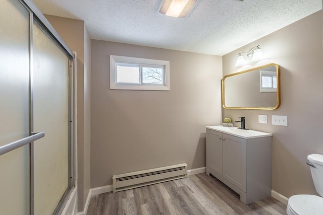 bathroom with hardwood / wood-style flooring, a baseboard heating unit, vanity, a textured ceiling, and toilet