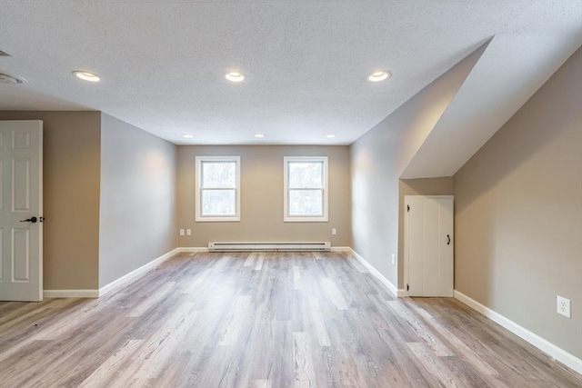 interior space featuring light wood-type flooring, a textured ceiling, and a baseboard heating unit