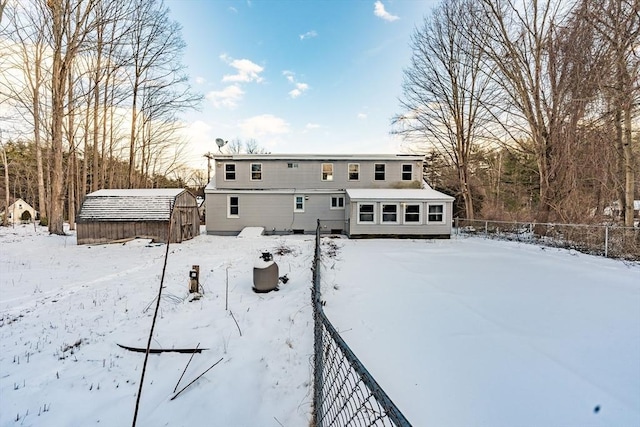 snow covered rear of property with a storage unit