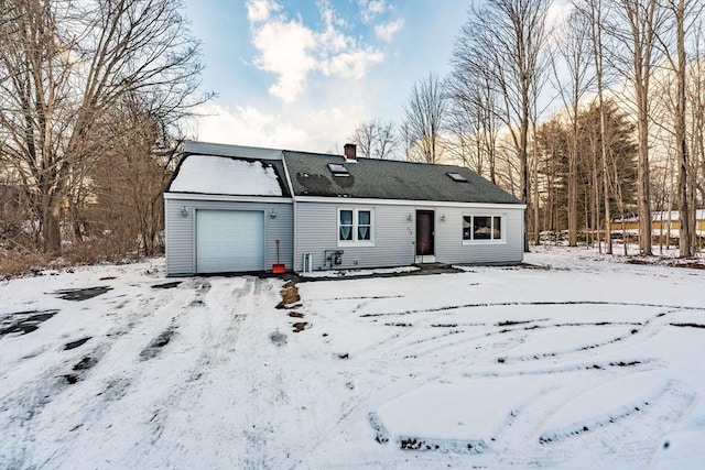 snow covered back of property with a garage