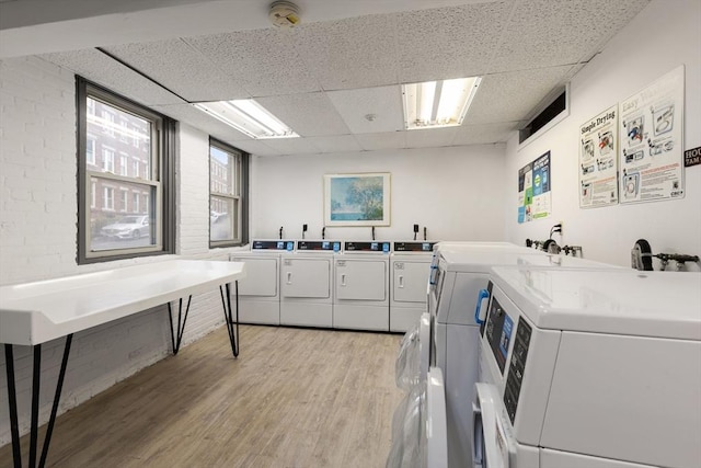 community laundry room with light wood-type flooring, independent washer and dryer, and plenty of natural light