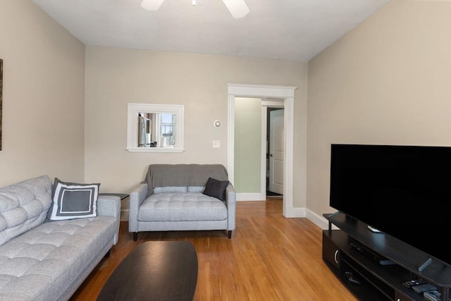 living area with light wood-type flooring, a ceiling fan, and baseboards