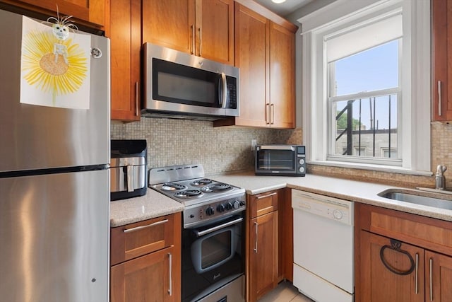 kitchen featuring stainless steel appliances, a sink, and brown cabinets