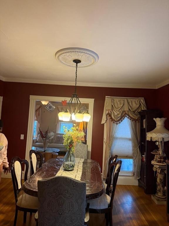 dining room with dark hardwood / wood-style flooring, crown molding, and an inviting chandelier