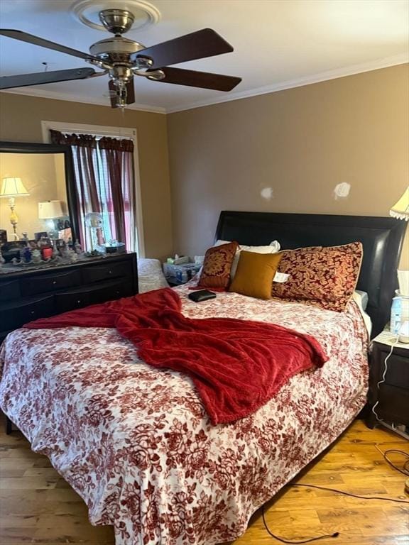 bedroom with wood-type flooring, ceiling fan, and crown molding