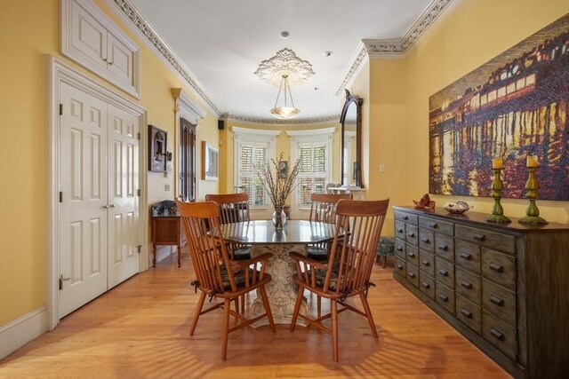dining room with baseboards, ornamental molding, and light wood-style floors