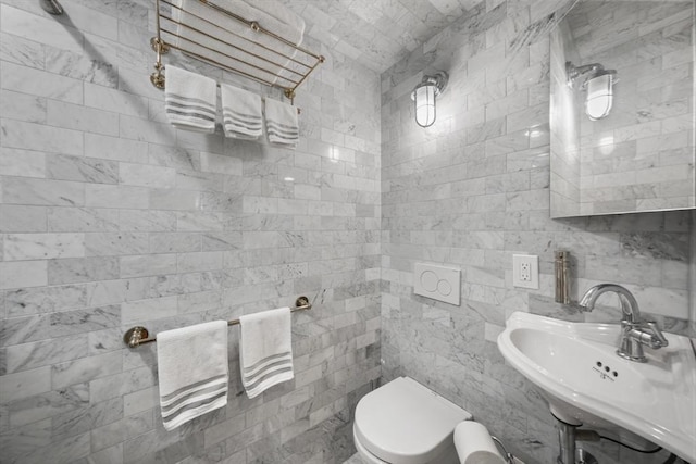 bathroom with tile walls, toilet, and a sink
