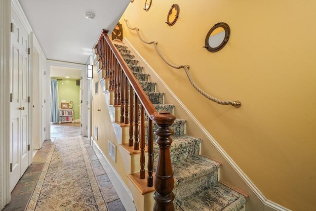 staircase with visible vents, baseboards, and stone tile floors