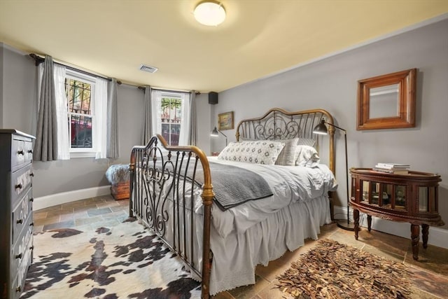 bedroom featuring stone finish flooring, baseboards, and visible vents