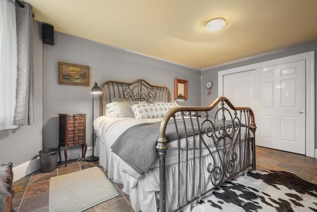 bedroom featuring baseboards, a closet, and stone tile flooring