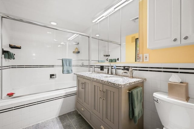 full bathroom with a sink, toilet, tile walls, visible vents, and tiled shower / bath