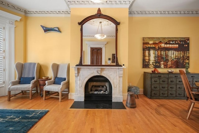 sitting room featuring a premium fireplace, ornamental molding, baseboards, and wood finished floors