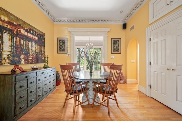 dining area featuring a chandelier, light wood-style flooring, arched walkways, and visible vents