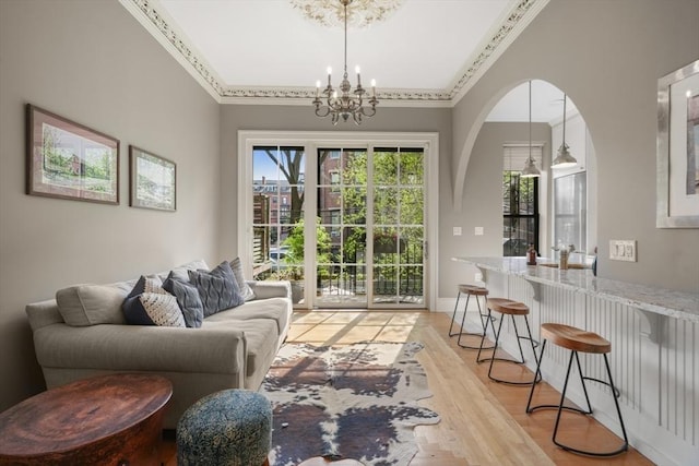 living room with ornamental molding, light wood-style flooring, and a chandelier