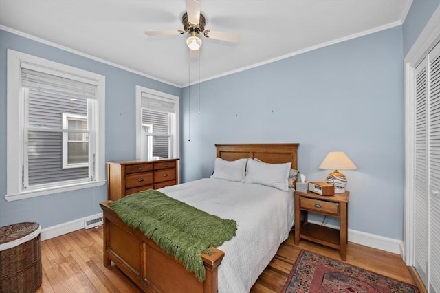 bedroom with a closet, light wood-style flooring, baseboards, and ornamental molding