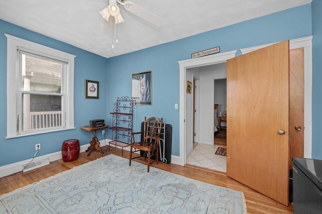 living area with ceiling fan, baseboards, visible vents, and light wood-type flooring