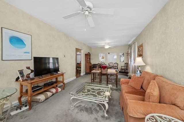 living room featuring carpet, baseboards, a textured wall, and ceiling fan