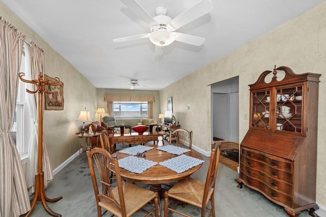 carpeted dining room with baseboards and ceiling fan