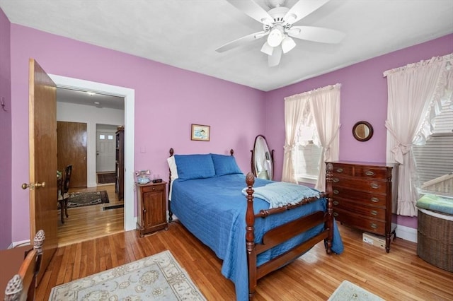 bedroom featuring baseboards, wood finished floors, and a ceiling fan