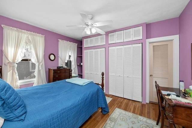 bedroom with a ceiling fan, wood finished floors, and multiple closets