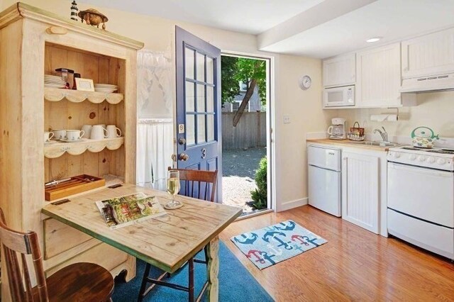 kitchen featuring sink, light hardwood / wood-style flooring, white appliances, white cabinets, and exhaust hood