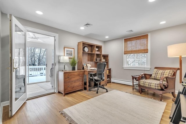 home office with a baseboard heating unit, ceiling fan, a wealth of natural light, and light hardwood / wood-style flooring