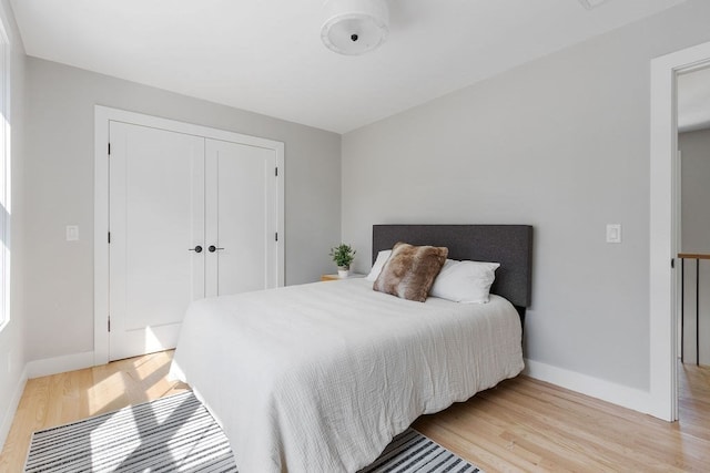 bedroom featuring light wood-type flooring, a closet, and multiple windows