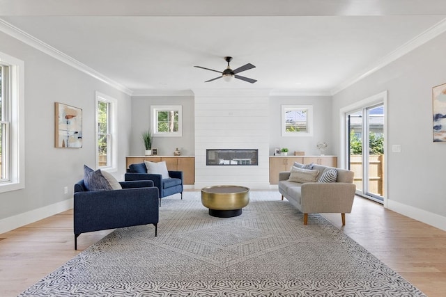 living room featuring a large fireplace, light hardwood / wood-style floors, ceiling fan, and plenty of natural light