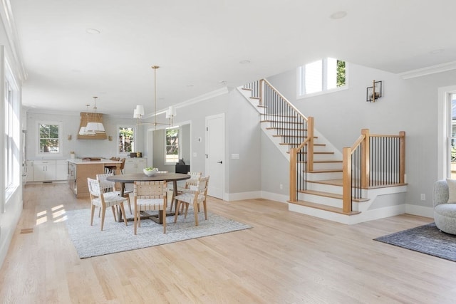 dining room with crown molding, light hardwood / wood-style floors, and an inviting chandelier